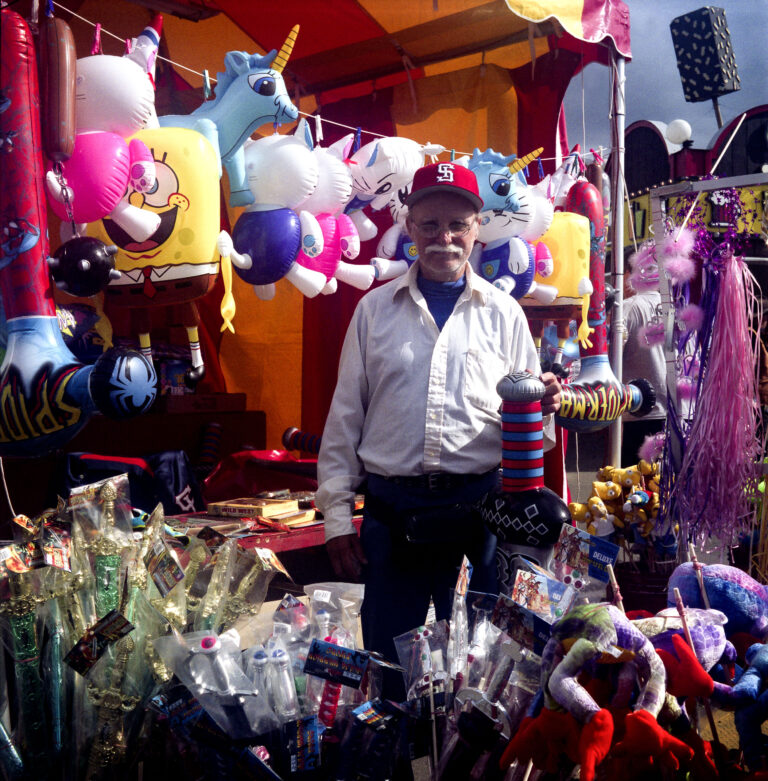 Vendor at carnival surrounded by so much stuff